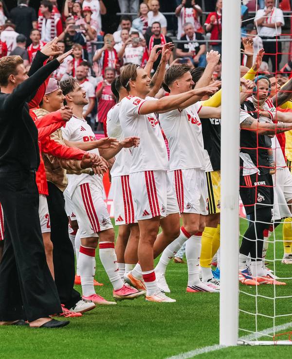 Die Profis des 1. FC Köln tanzen vor der Fankurve.