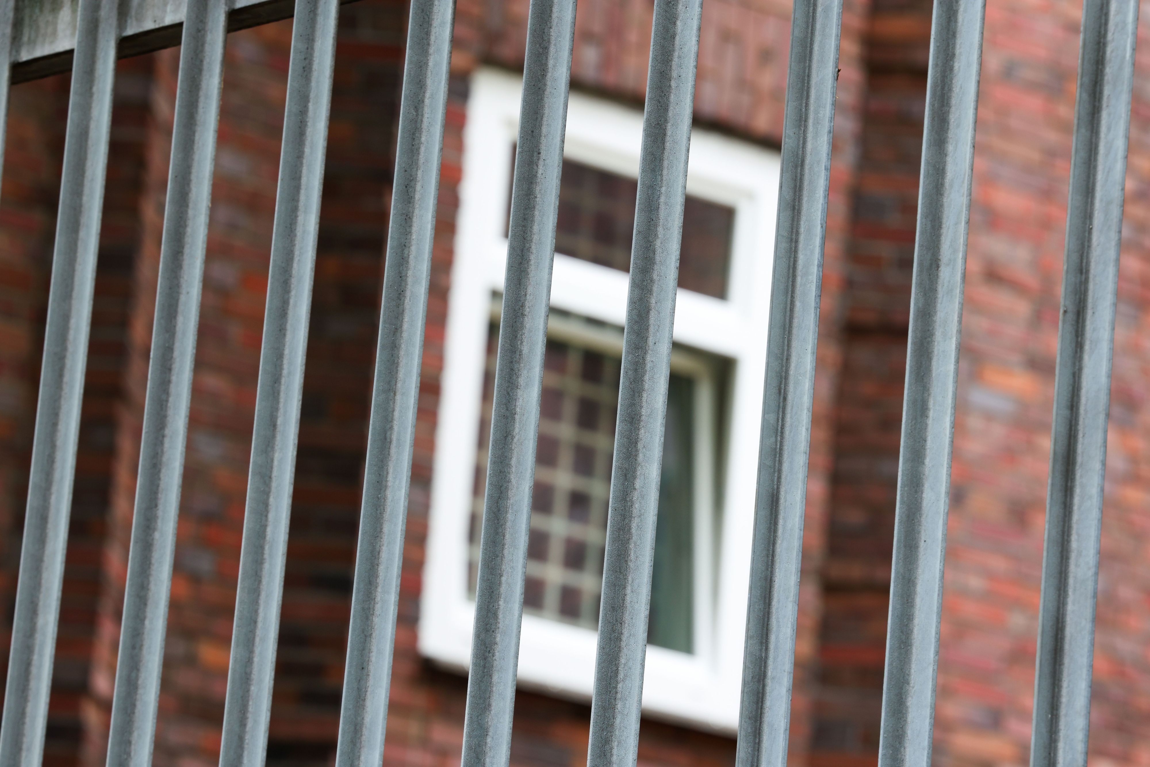 Vergitterte Fenster an der JVA Duisburg-Hamborn, davor ein Zaun.