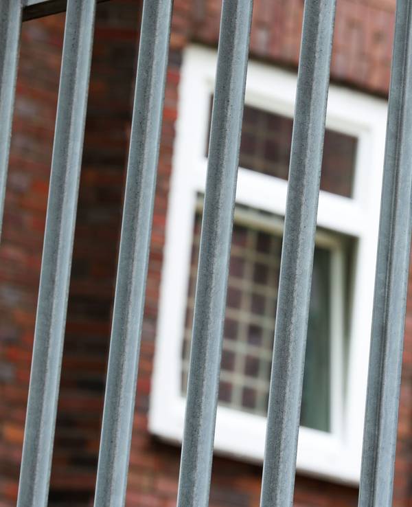 Vergitterte Fenster an der JVA Duisburg-Hamborn, davor ein Zaun.