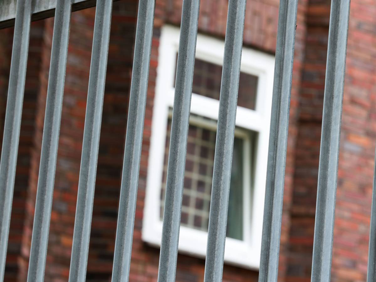 Vergitterte Fenster an der JVA Duisburg-Hamborn, davor ein Zaun.