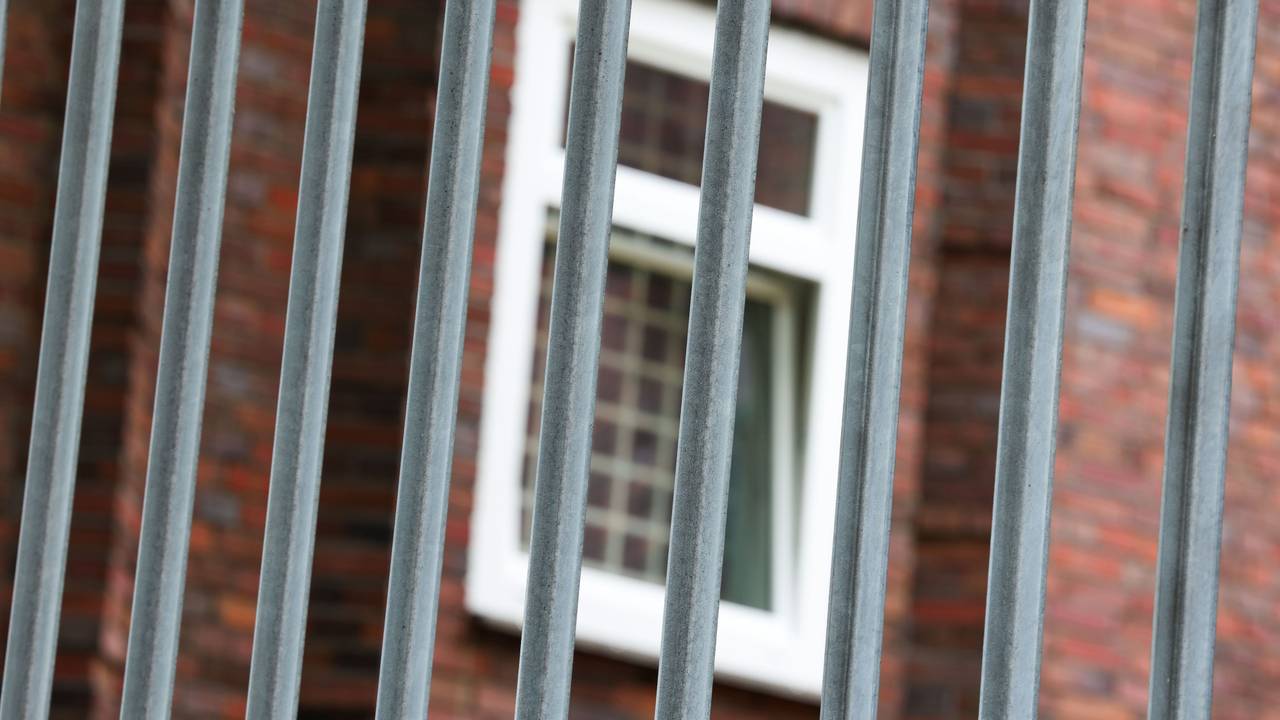 Vergitterte Fenster an der JVA Duisburg-Hamborn, davor ein Zaun.