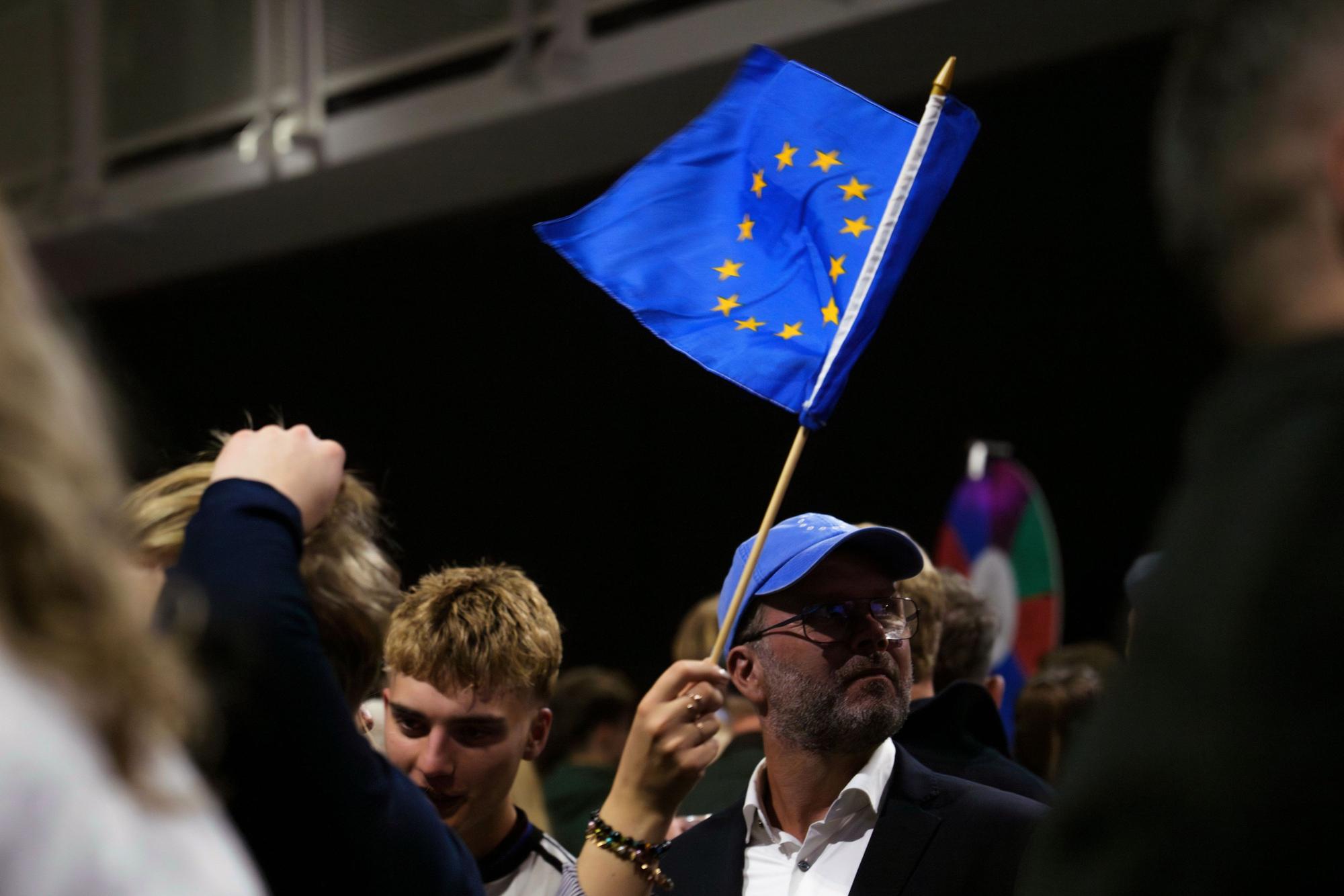 30.08.2026, Island, Reykjavík: Ein Mann schwenkt eine Fahne der Europäischen Union, während einer Wahlnachtveranstaltung der «Ja»-Kampagne. Foto: Marco Di Marco/AP/dpa +++ dpa-Bildfunk +++