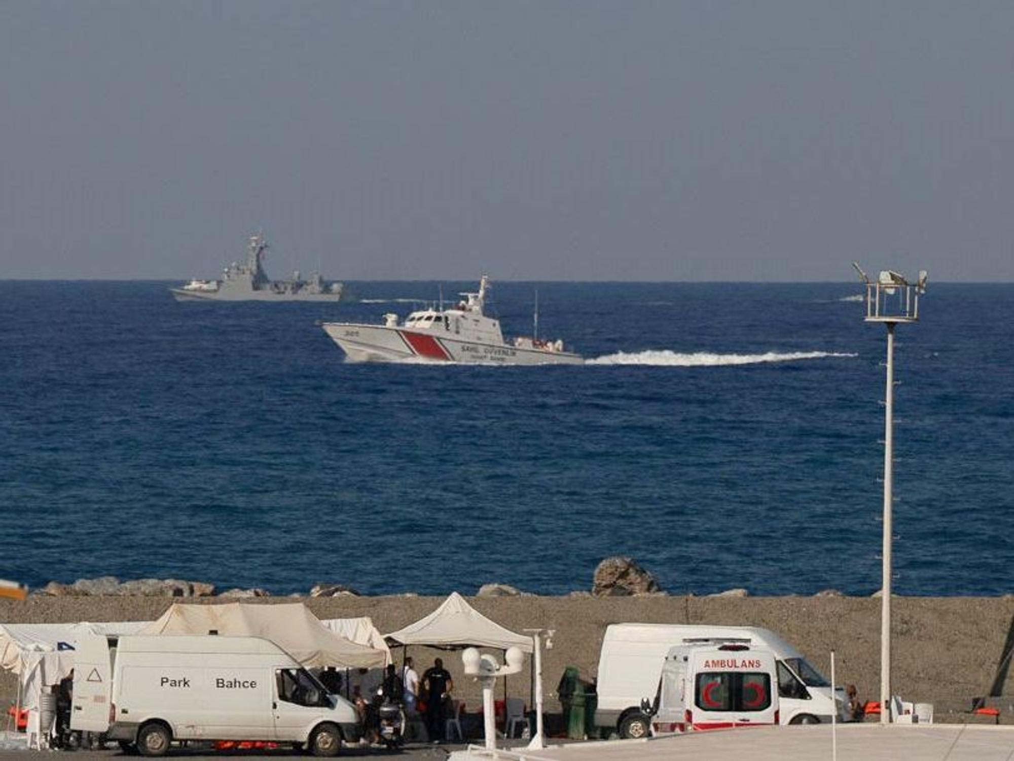 Schiffe fahren in der Nähe des Hafens von Kyrenia vorbei, während im türkisch besetzten Norden Zyperns ein Krankenwagen am Ufer geparkt ist, nachdem vor der Nordküste der Insel eine Passagierfähre gekentert war.