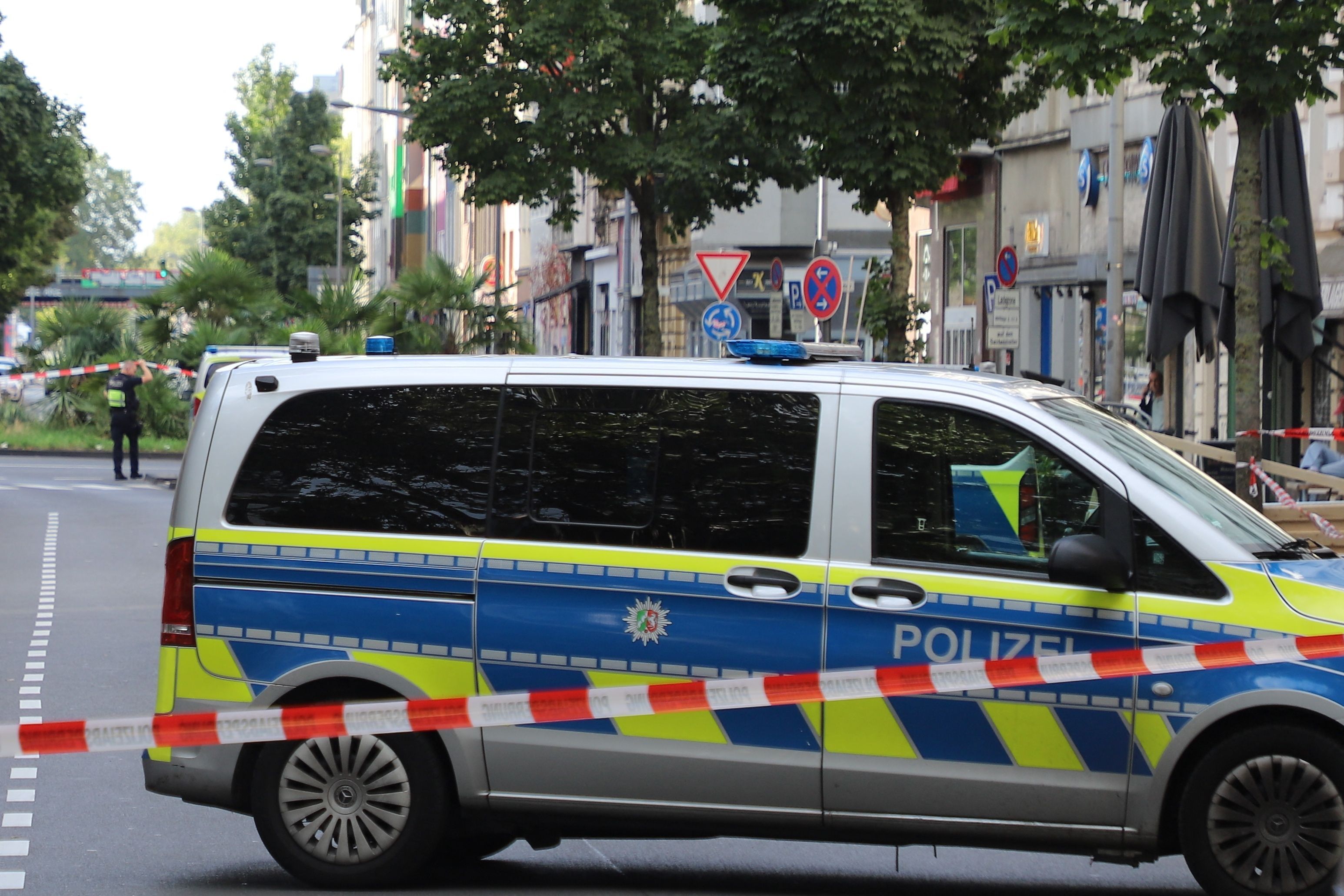 Ein Fahrzeug der Polizei steht hinter einer Absperrung auf einer Straße.