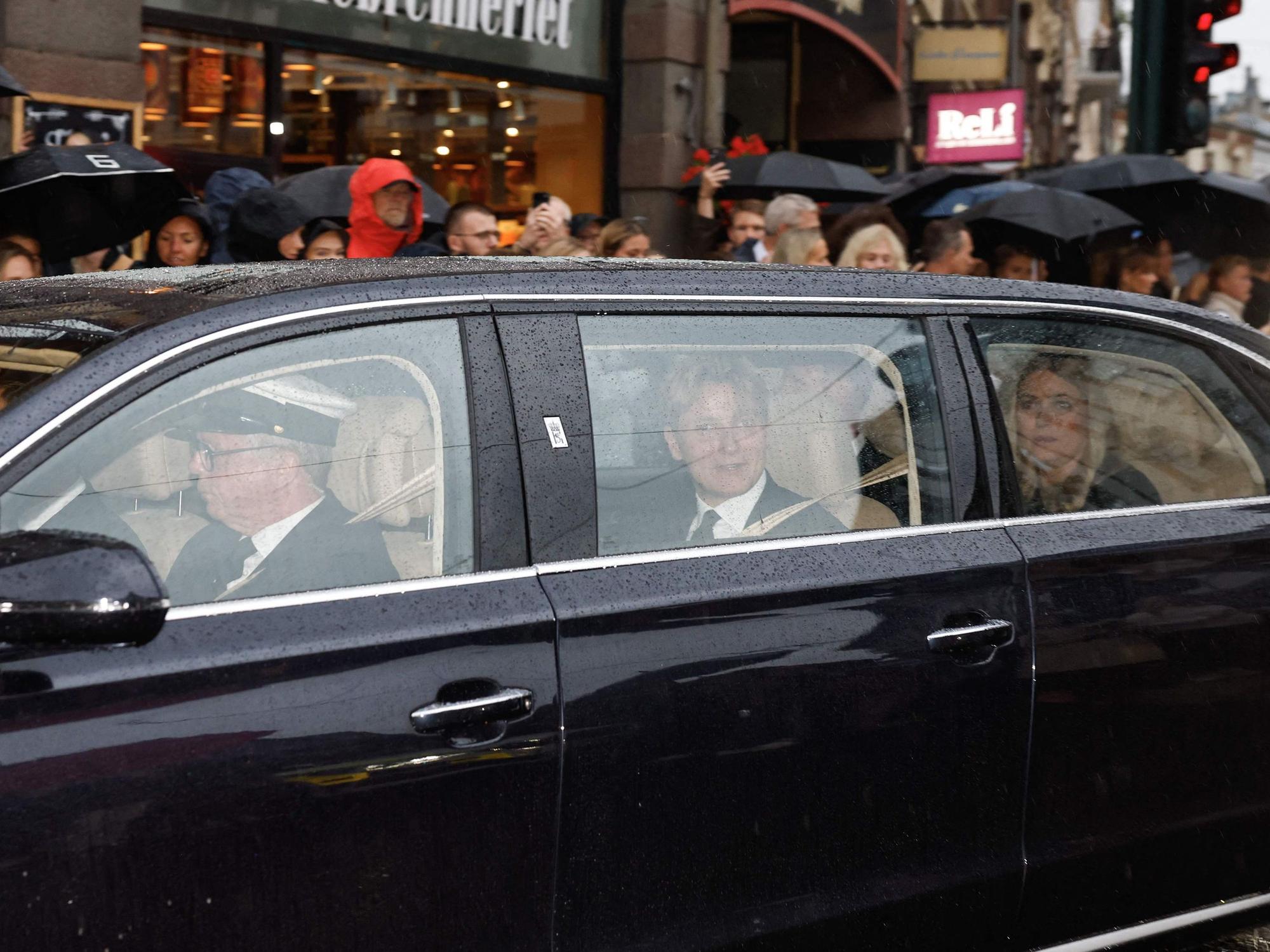 Norwegens neue Königin Mette-Marit (r.) und Norwegens Prinz Sverre Magnus (M.) sitzen in einem Auto hinter dem Leichenwagen mit dem verstorbenen König Harald V. von Norwegen, während dieser am 28. August 2026 durch Oslo in Richtung des Königlichen Schlosses fährt.