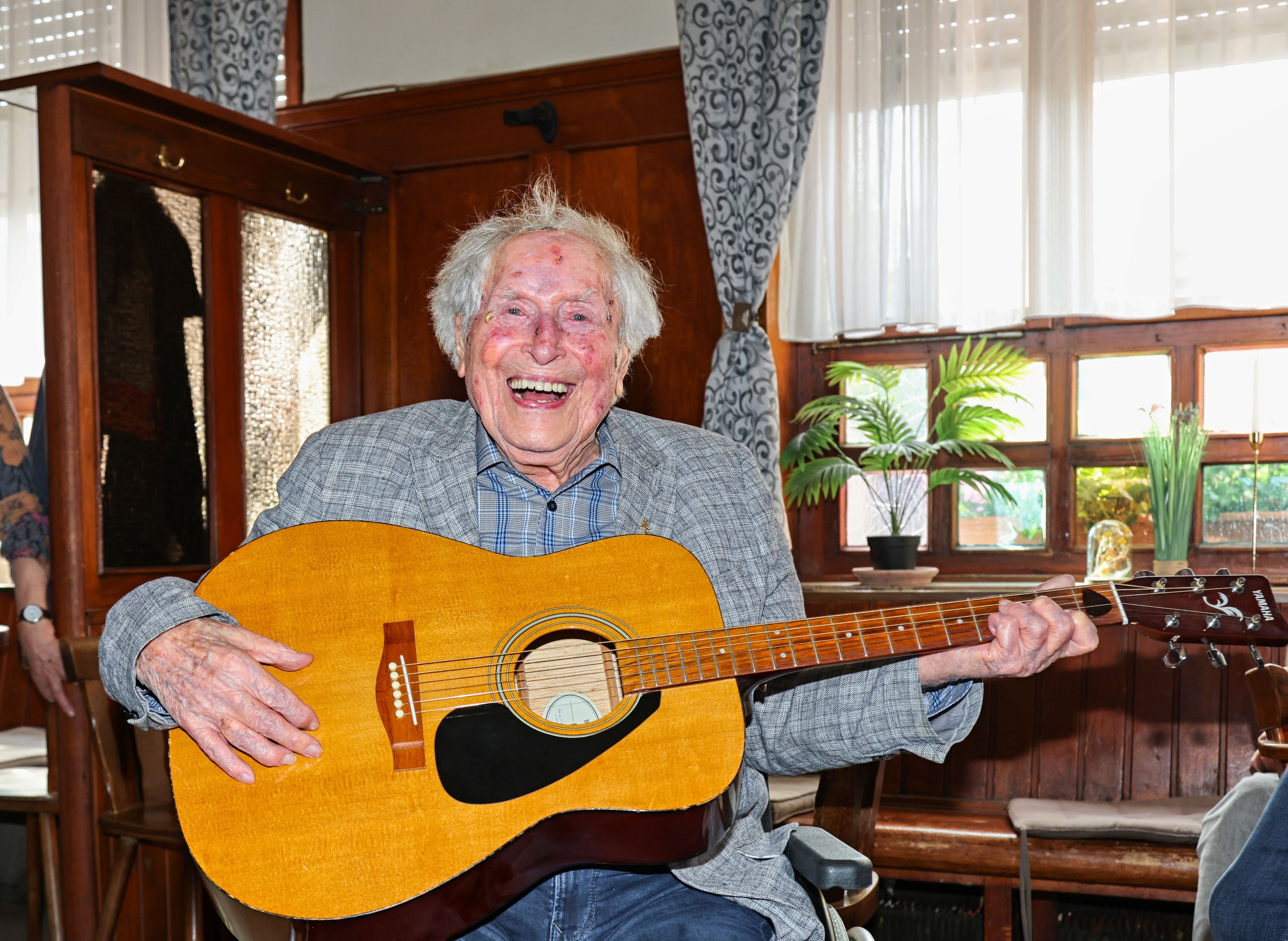 Ludwig Sebus sitzt mit einer Gitarre in der Wirtschaft.