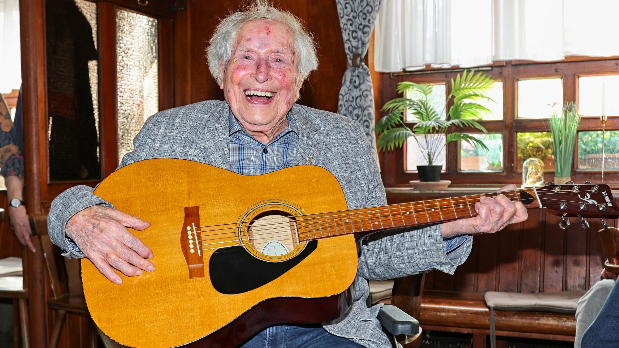 Ludwig Sebus sitzt mit einer Gitarre in der Wirtschaft.