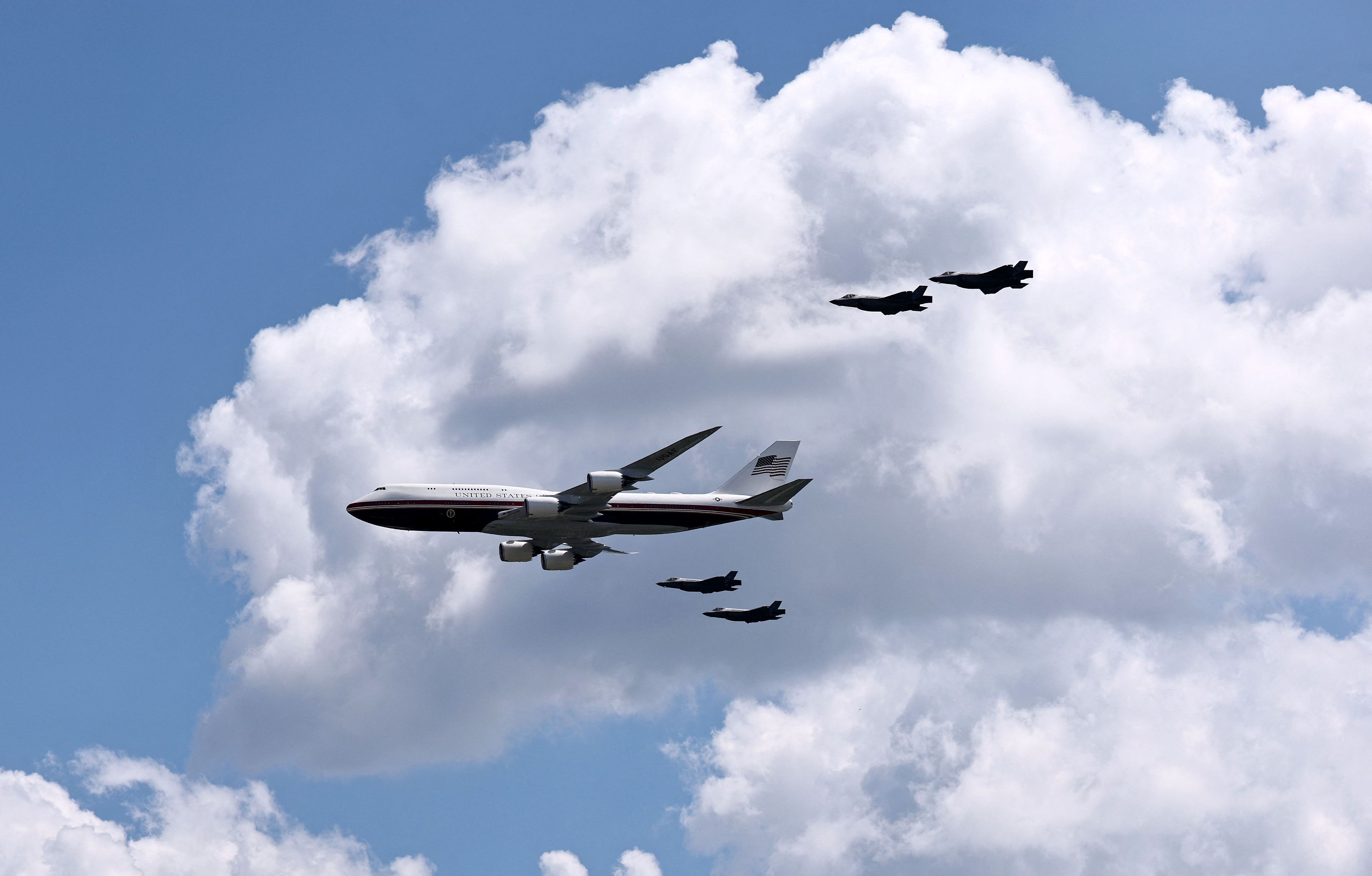 Die Air Force One mit vier Kampfjets bei einem Flyover.