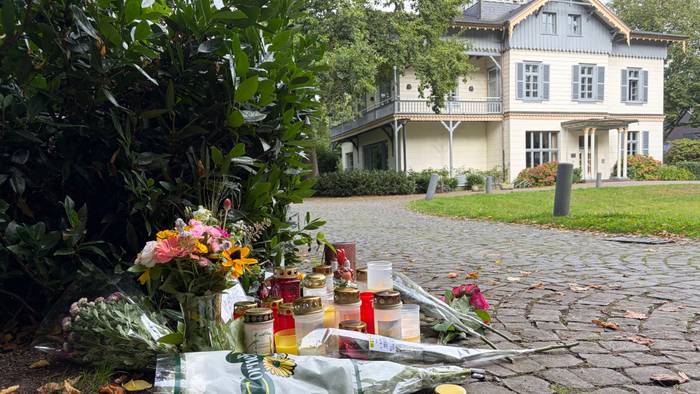 An einem Tatort liegen Blumensträuße, stehen Kerzen.
