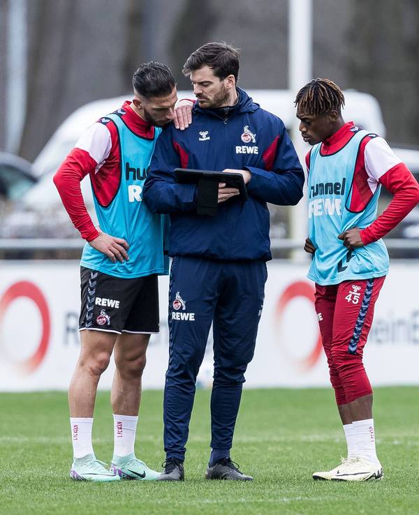 Max Weuthen steht mit Leart Paqarada und Justin Diehl auf dem Trainingsplatz und zeigt ihnen etwas auf dem Tablet.