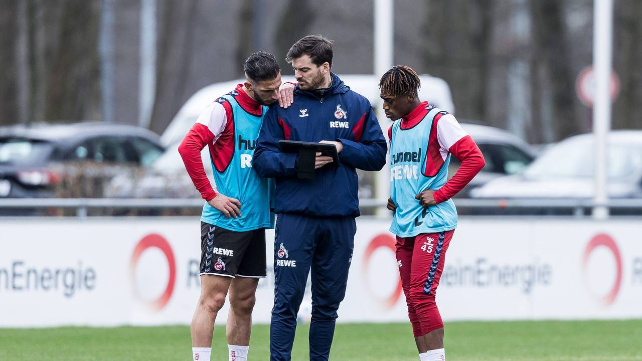 Max Weuthen steht mit Leart Paqarada und Justin Diehl auf dem Trainingsplatz und zeigt ihnen etwas auf dem Tablet.