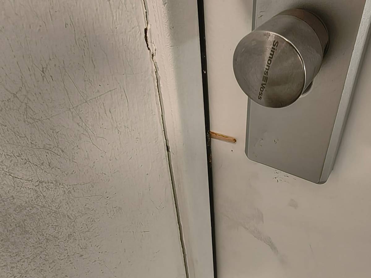 Ein Zahnstocher steckt zwischen Haustür und Türrahmen.