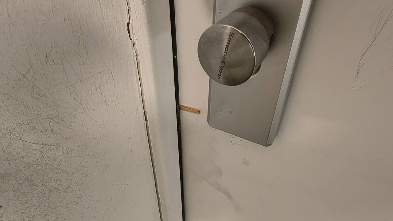 Ein Zahnstocher steckt zwischen Haustür und Türrahmen.