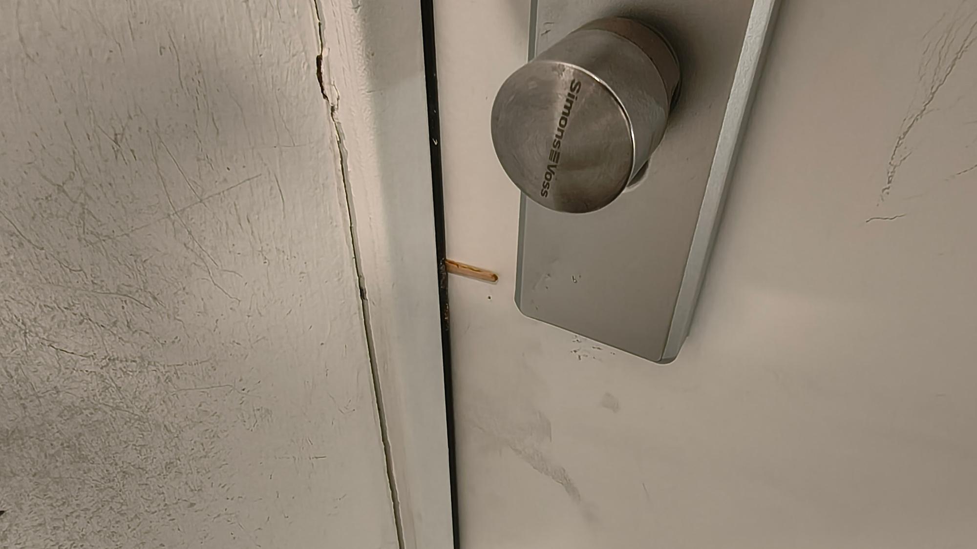 Ein Zahnstocher steckt zwischen Haustür und Türrahmen.