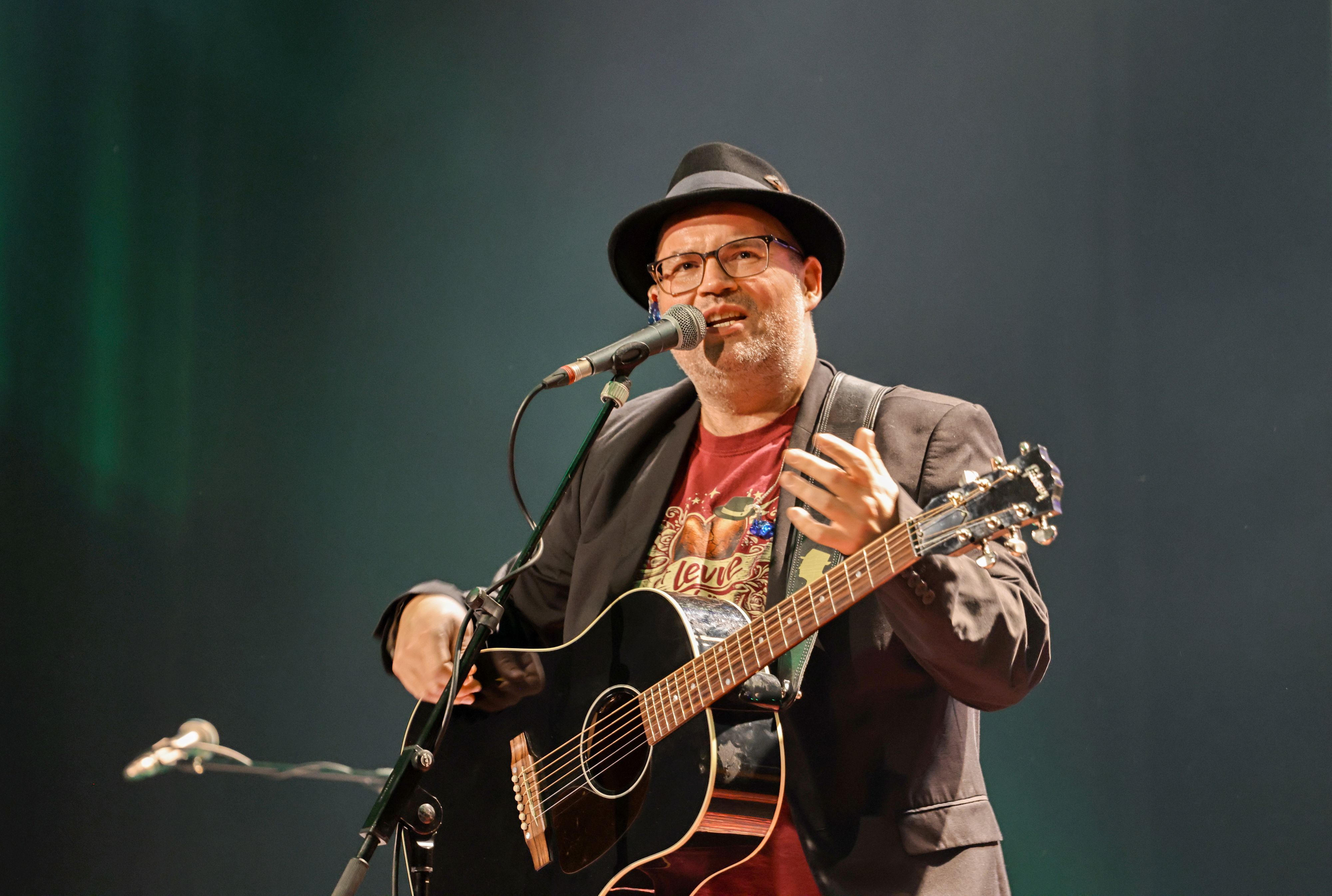 Björn Heuser steht mit Gitarre auf der Bühne.