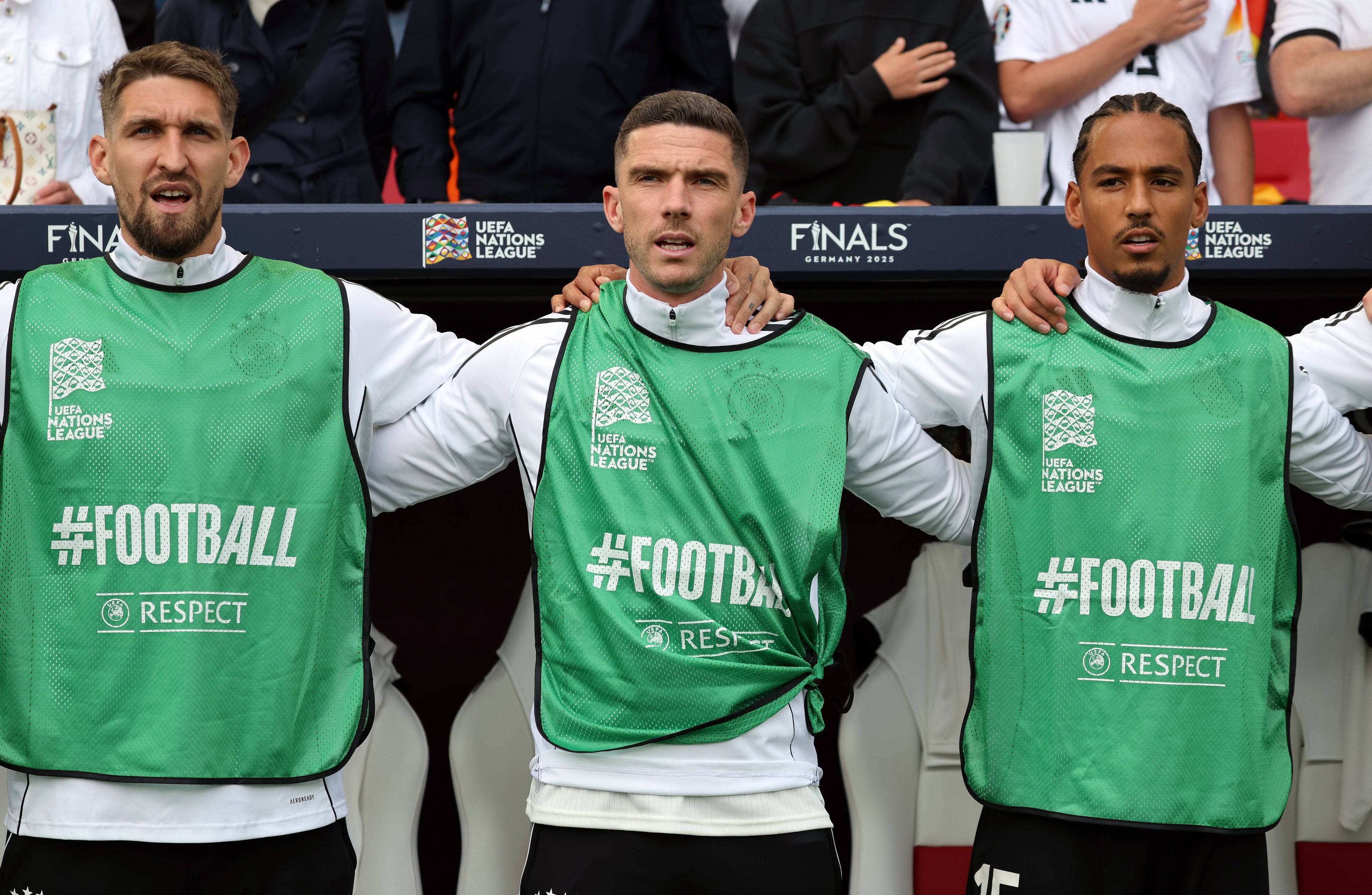 Robert Andrich, Robin Gosens und Thilo Kehrer stehen Arm in Arm und singen die Hymne.