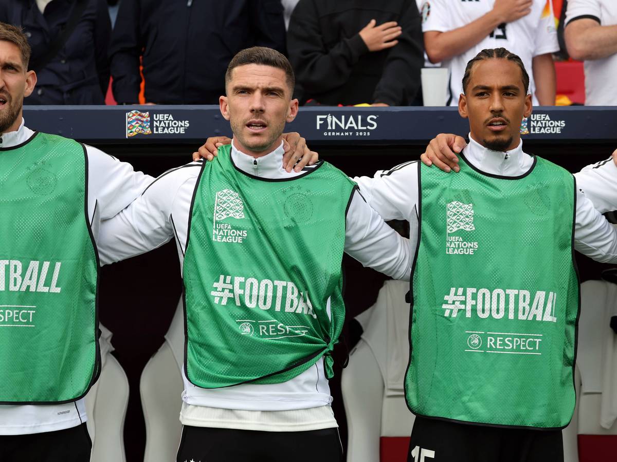 Robert Andrich, Robin Gosens und Thilo Kehrer stehen Arm in Arm und singen die Hymne.