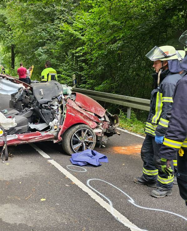 Ein Autowrack steht quer auf der Fahrbahn, Feuerwehrleute sind im Einsatz.