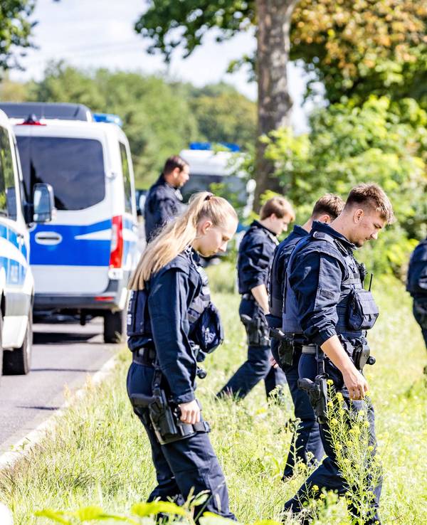 Einsatzkräfte einer Polizeihundertschaft durchsuchen großräumig die Umgebung. Nach der Sabotage am Stromnetz in Südbrandenburg sucht die Polizei vor Ort weiter nach Spuren, um die Täter zu ermitteln.