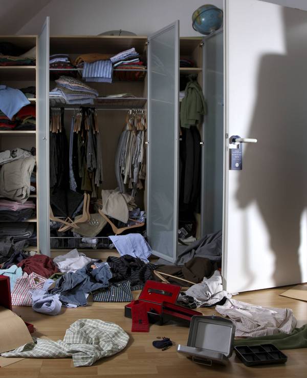 Kleidung und Schachteln wurde aus einem Schrank gerissen und auf den Fußboden geworfen, auf der Zimmertür ist der Schatten eines Einbrechers zu sehen.