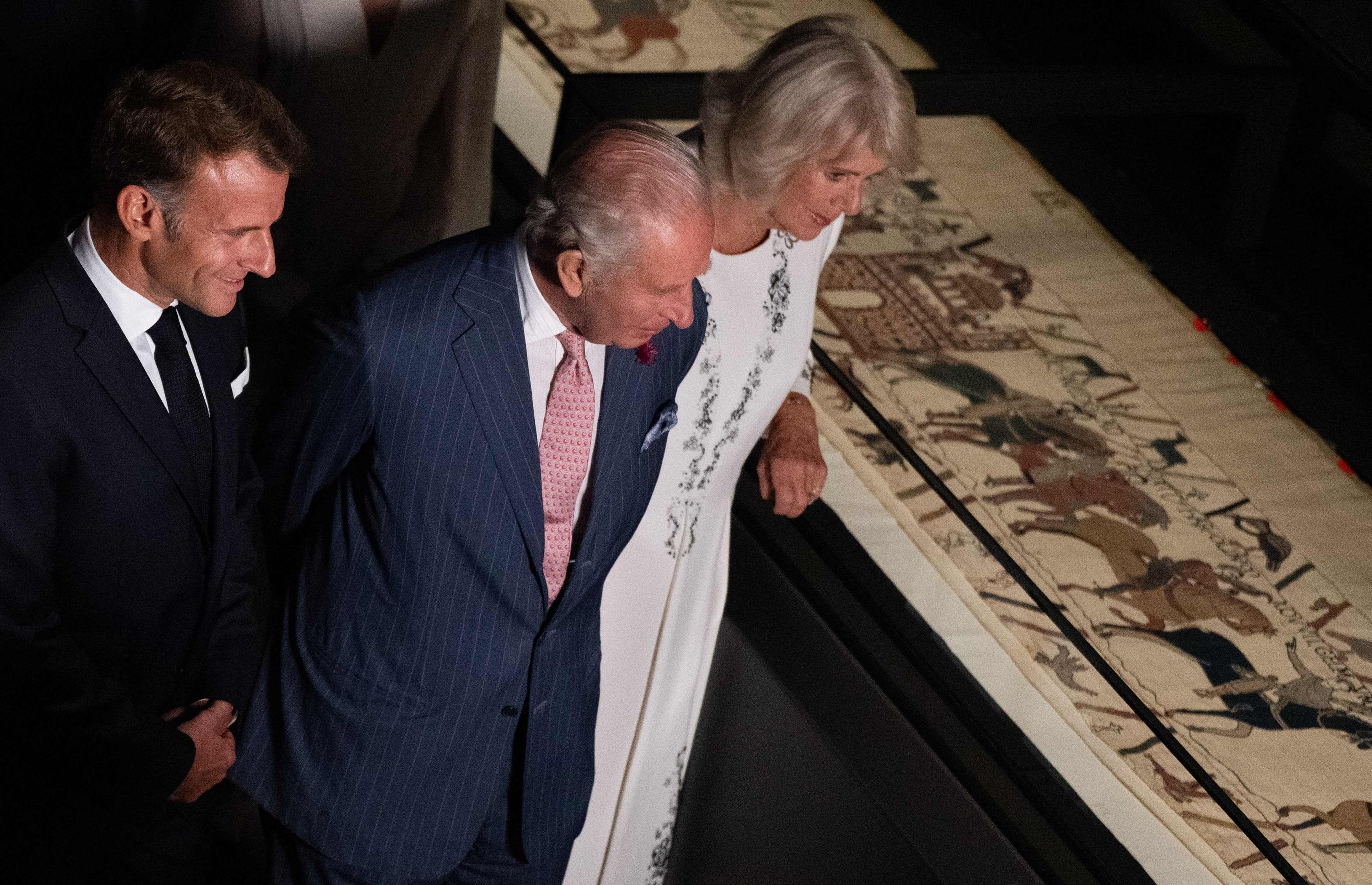 Emmanuel Macron, König Charles III. und Königin Camilla betrachten bei einer Vorbesichtigung im British Museum Teile des historischen Teppichs von Bayeux.