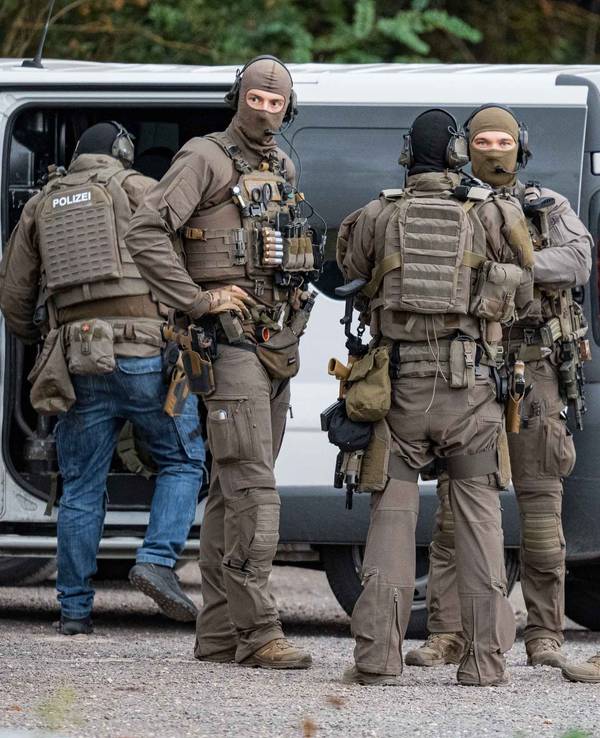 Vermummte und schwer bewaffnete Polizisten sind im Einsatz.