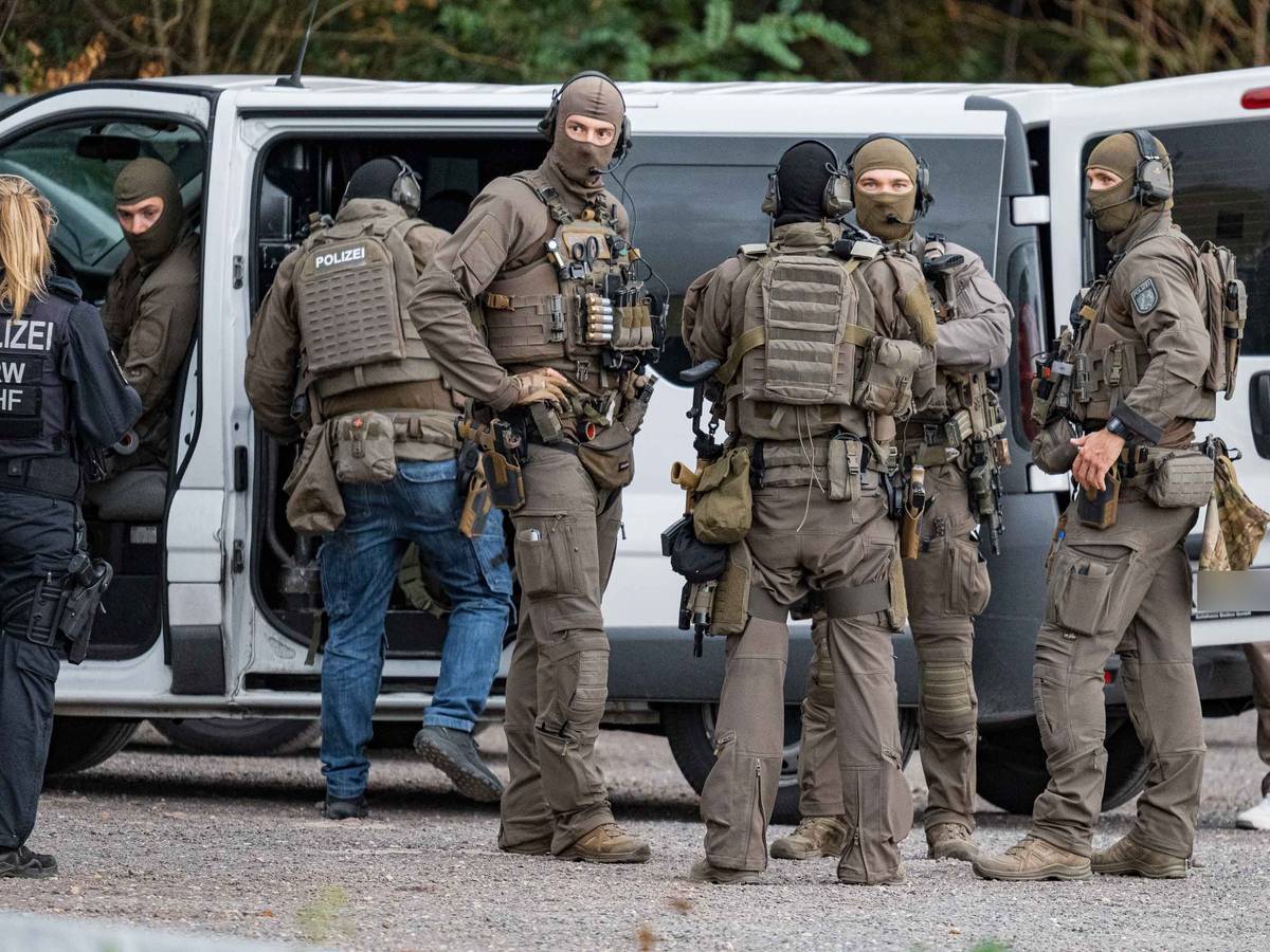 Vermummte und schwer bewaffnete Polizisten sind im Einsatz.