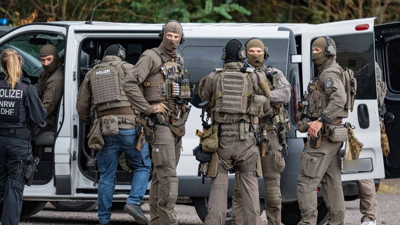 Vermummte und schwer bewaffnete Polizisten sind im Einsatz.