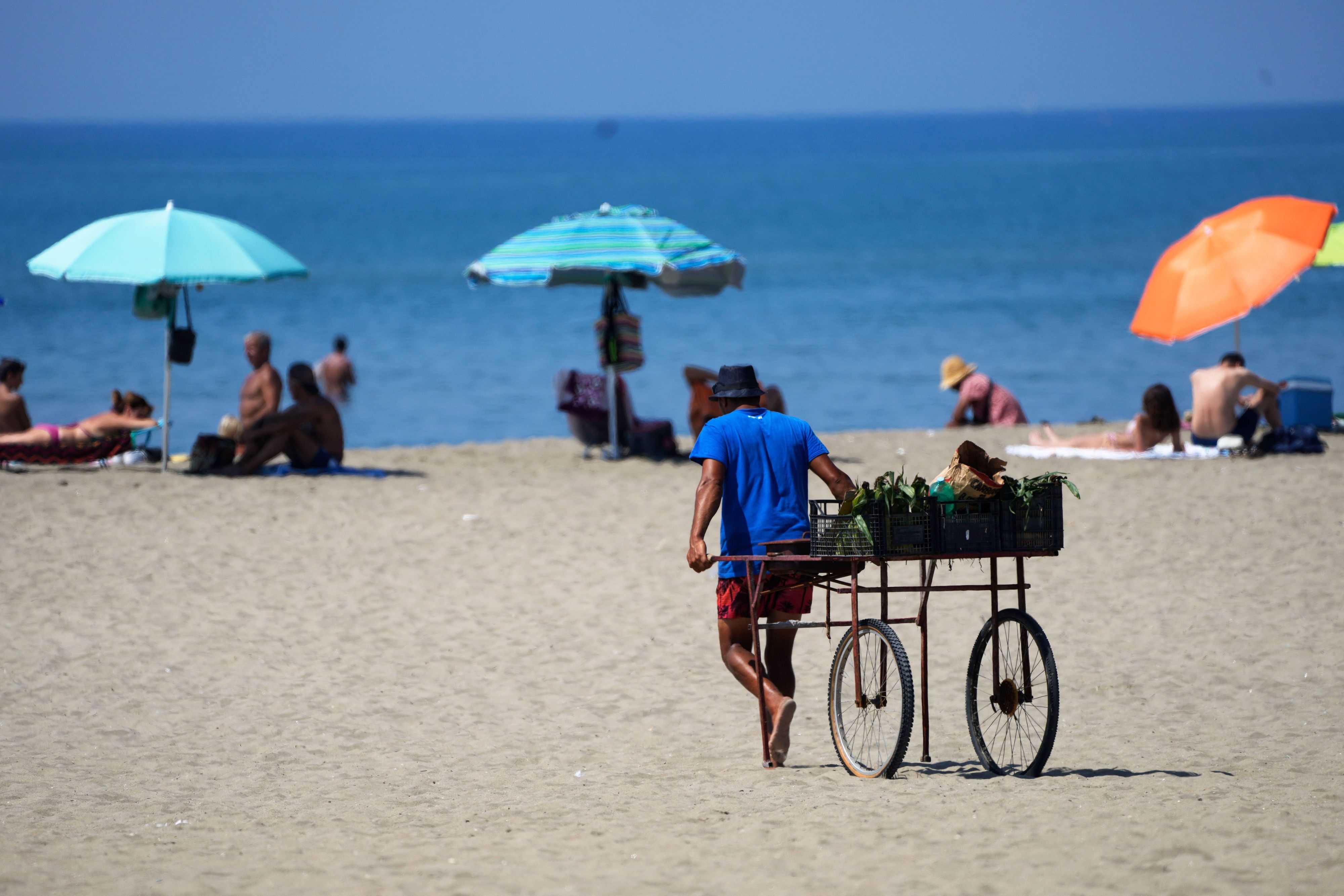 Ein Strandverkäufer zieht seinen Wagen an einem Strand in der Nähe von Rom hinter sich her.