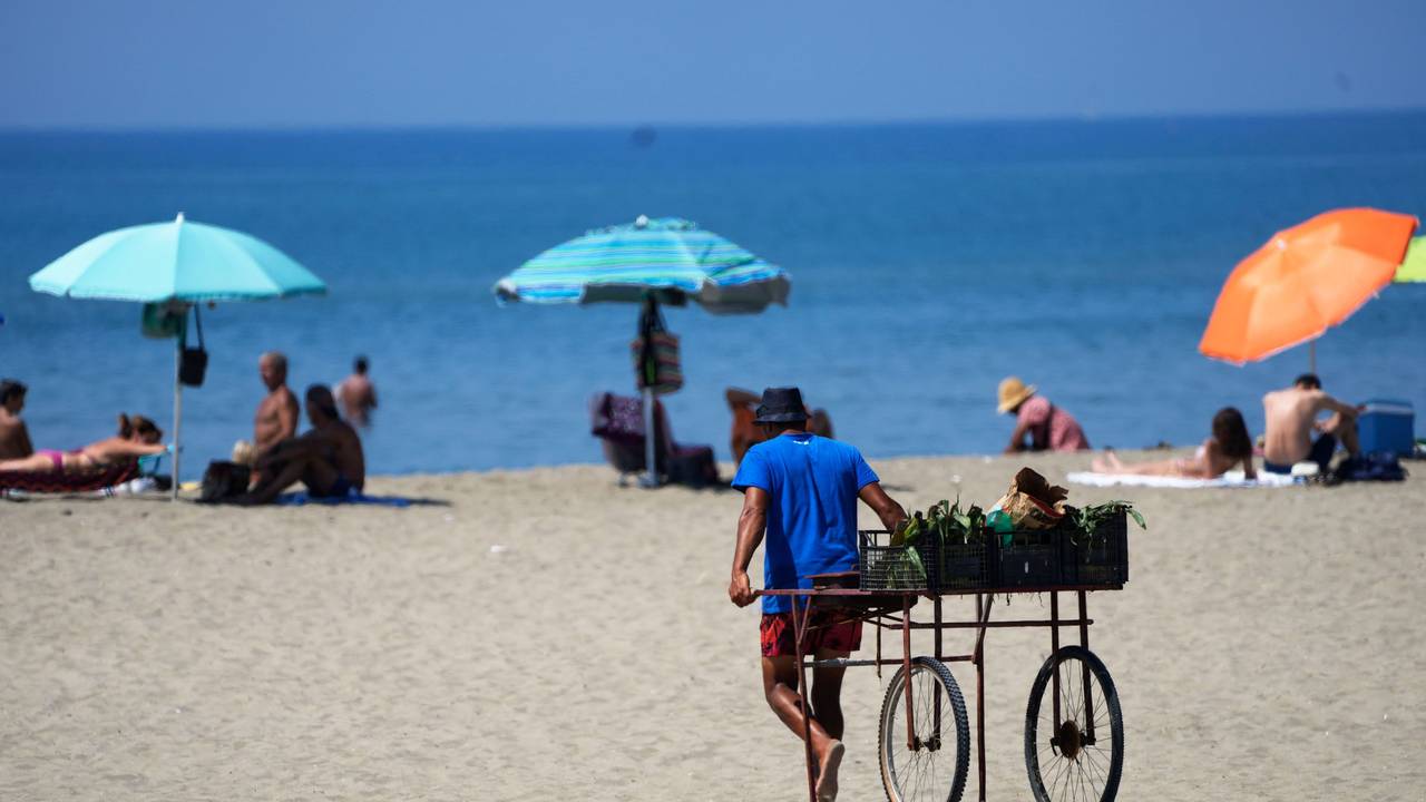 Ein Strandverkäufer zieht seinen Wagen an einem Strand in der Nähe von Rom hinter sich her.