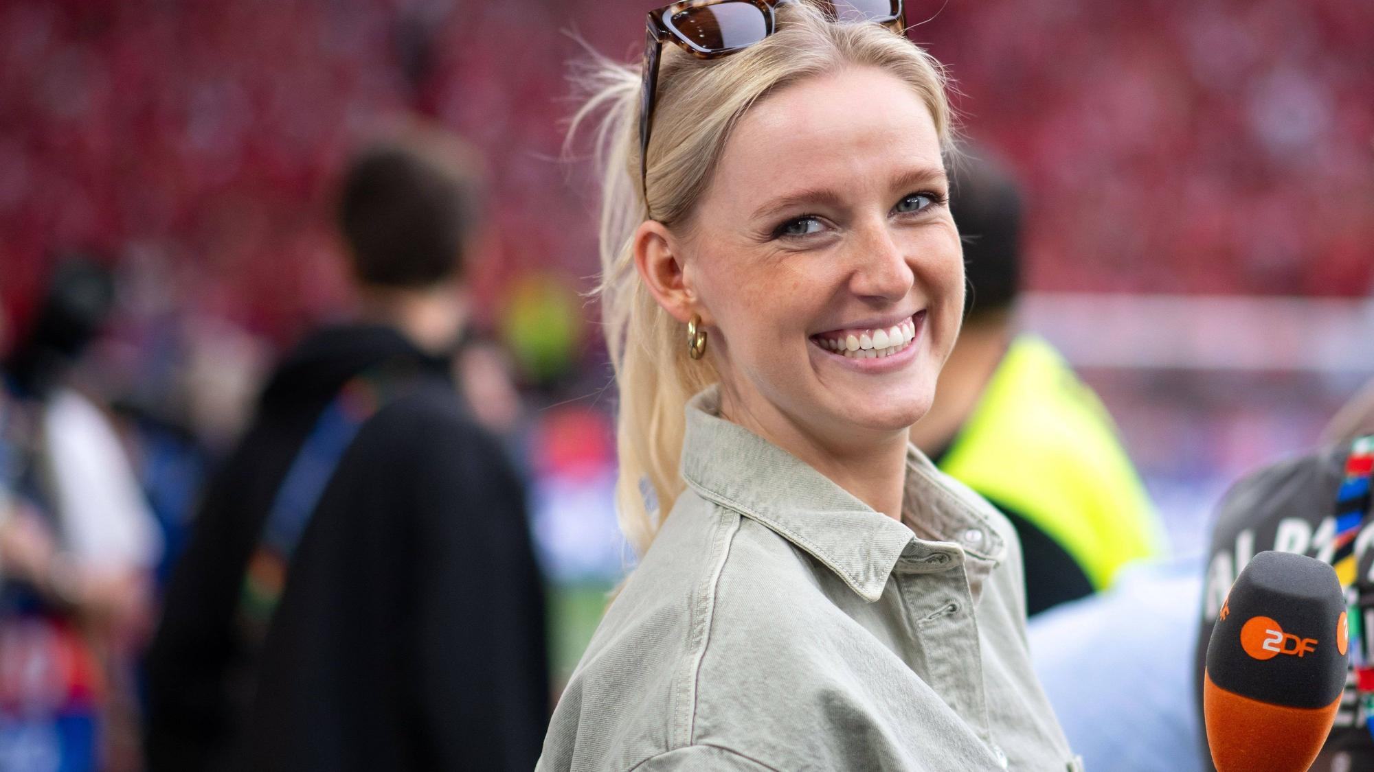 Franziska Müllers lächelt und hält ein Mikrofon