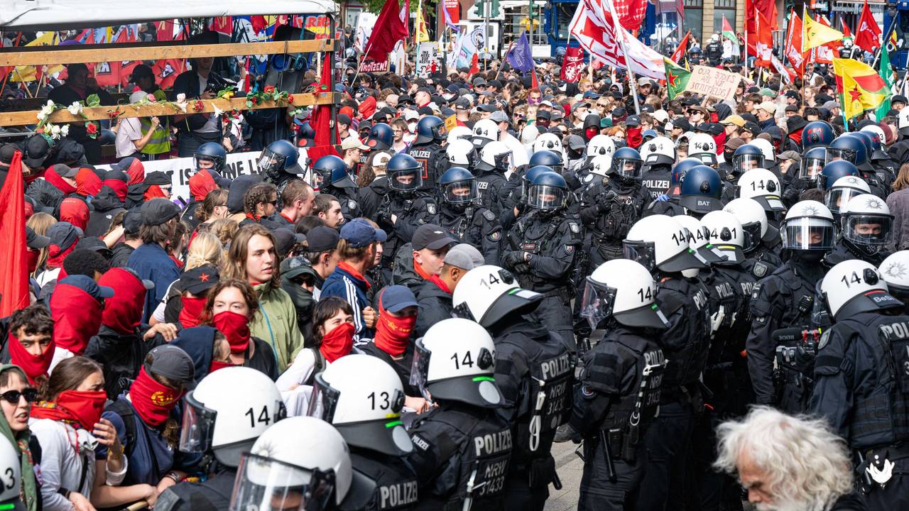Polizeikräfte mit Schutzhelmen umringen Demoteilmende, von denen viele vermummt sind.