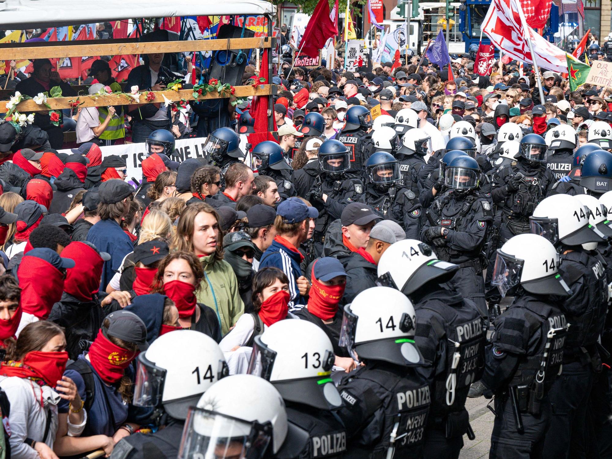 Polizeikräfte mit Schutzhelmen umringen Demoteilmende, von denen viele vermummt sind.