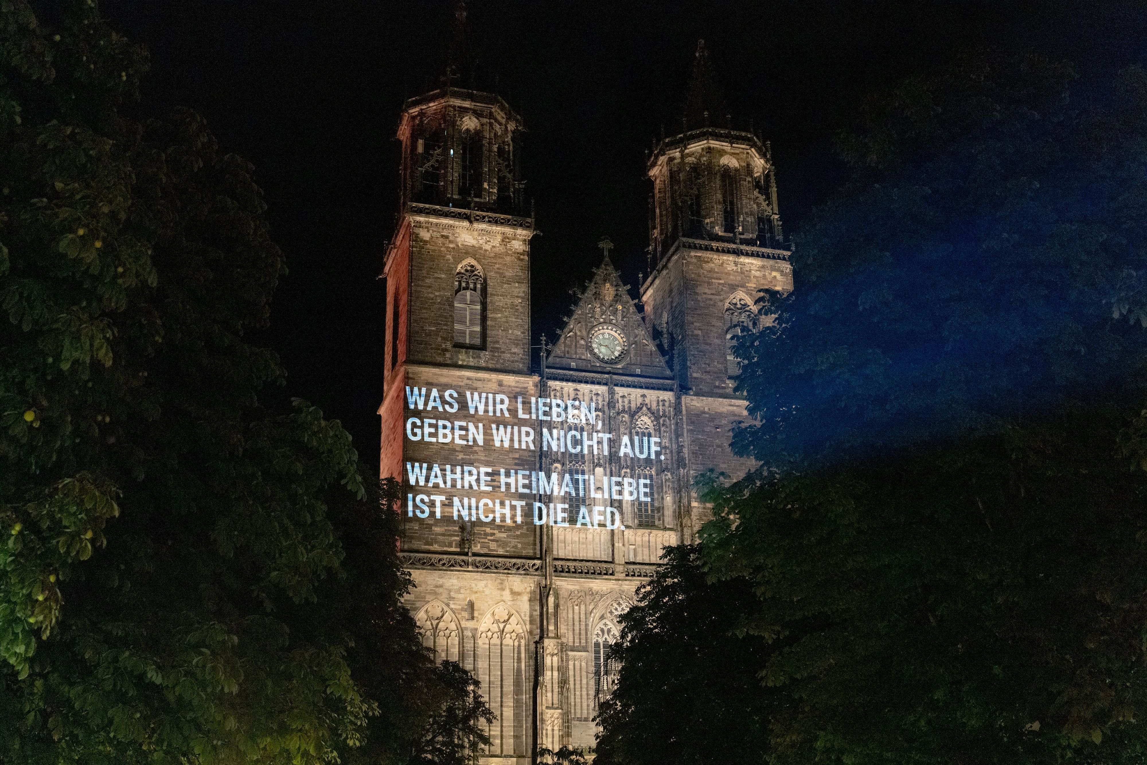 Aktivisten projizieren den Spruch „Was wir lieben, geben wir nicht auf. Wahre Heimatliebe ist nicht die AfD.“ auf die Fassade des Magdeburger Doms.