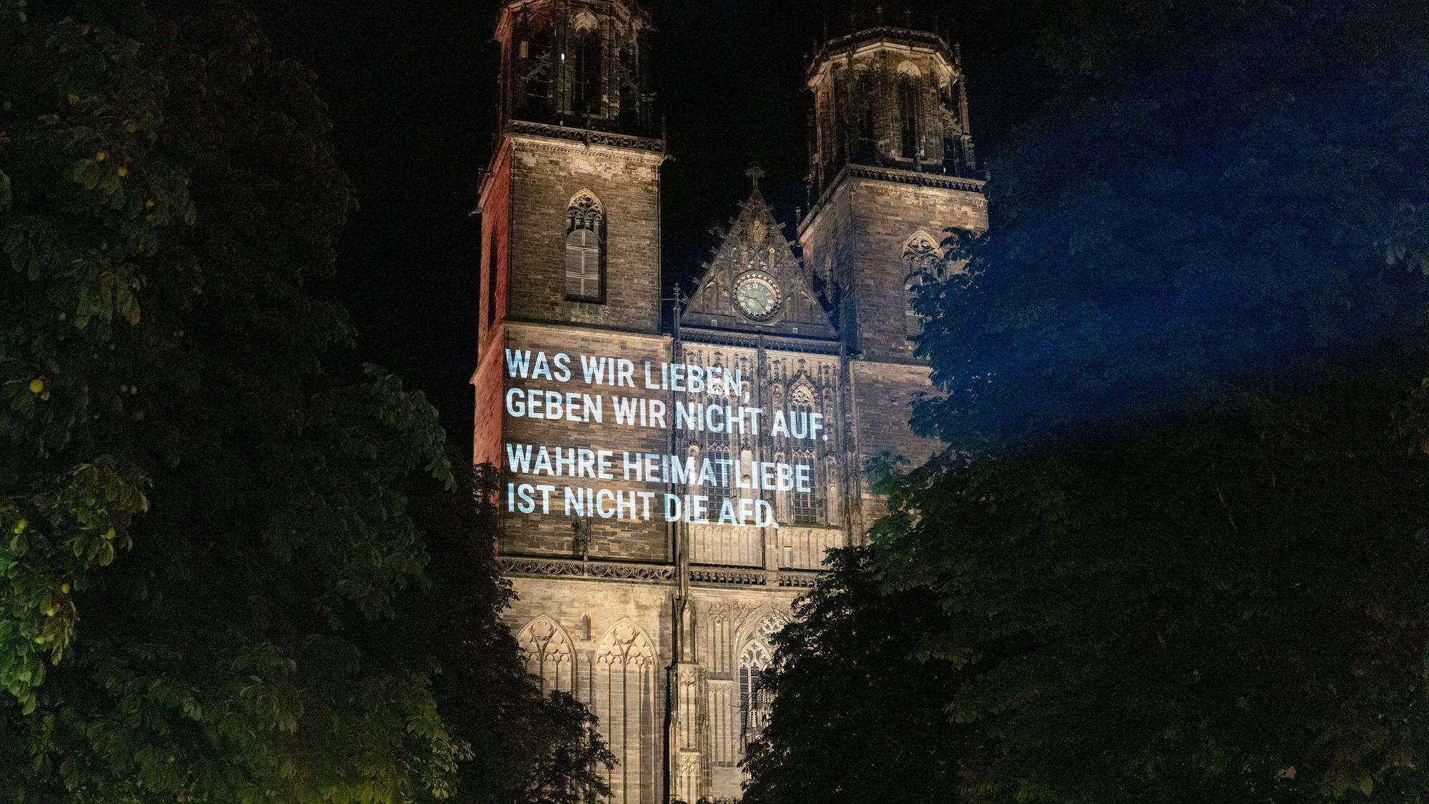 Aktivisten projizieren den Spruch „Was wir lieben, geben wir nicht auf. Wahre Heimatliebe ist nicht die AfD.“ auf die Fassade des Magdeburger Doms.
