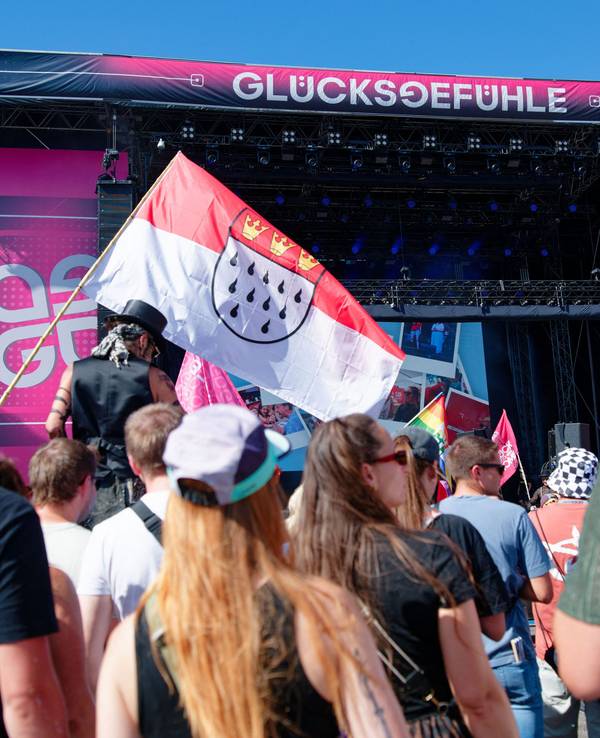 04.09.2026, Baden-Württemberg, Hockenheim: Besucher stehen vor einer Bühne beim Glücksgefühle-Festival auf dem Hockenheimring und halten eine Kölner Stadtflagge. Foto: Uwe Anspach/dpa +++ dpa-Bildfunk +++