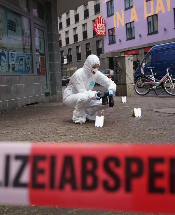 Ein Beamter der Spurensicherung sichert Blutspuren auf dem Gehweg, der mit Polizeiflatterband abgesperrt ist.