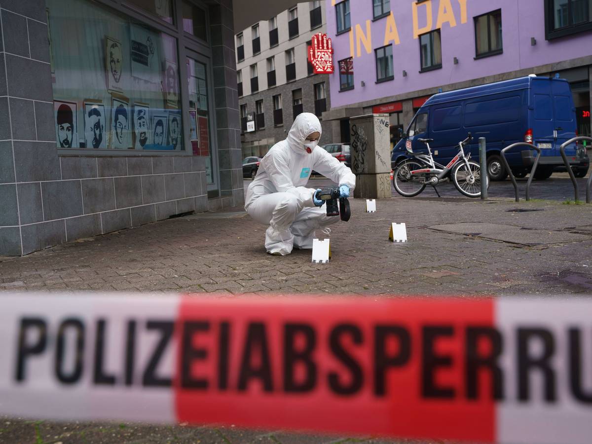 Ein Beamter der Spurensicherung sichert Blutspuren auf dem Gehweg, der mit Polizeiflatterband abgesperrt ist.
