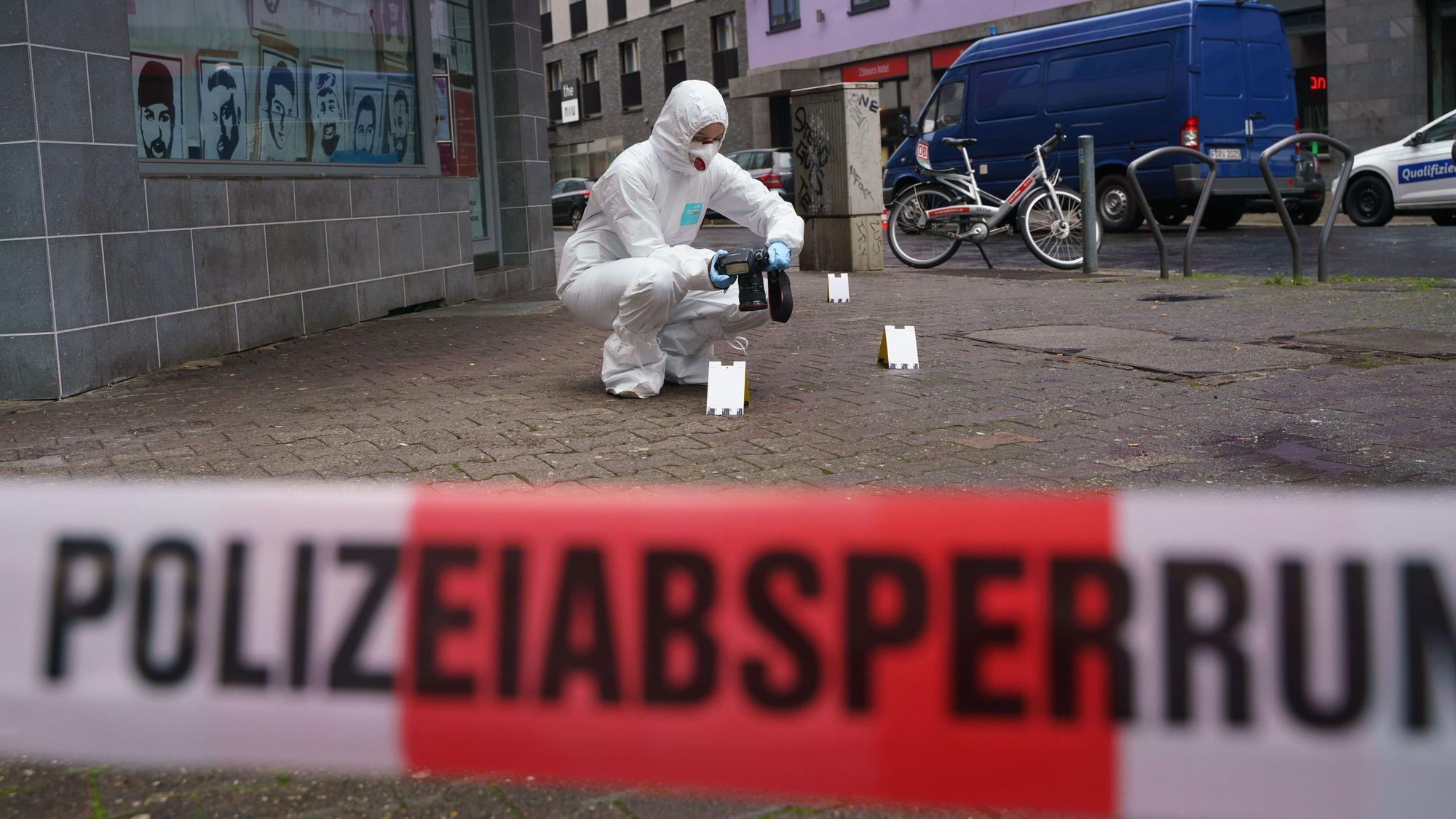 Ein Beamter der Spurensicherung sichert Blutspuren auf dem Gehweg, der mit Polizeiflatterband abgesperrt ist.