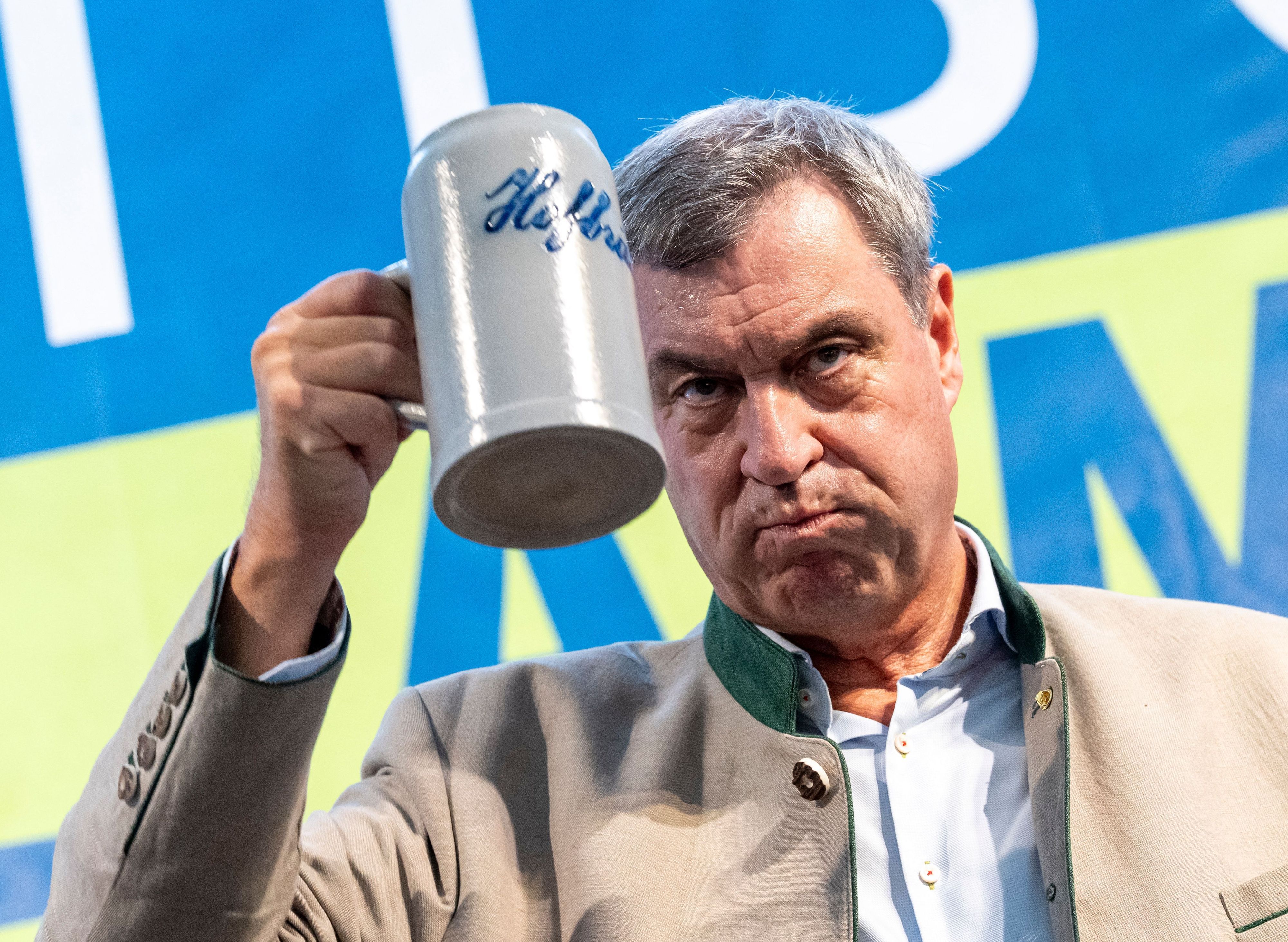 Markus Söder hält ein Getränk in der Hand.
