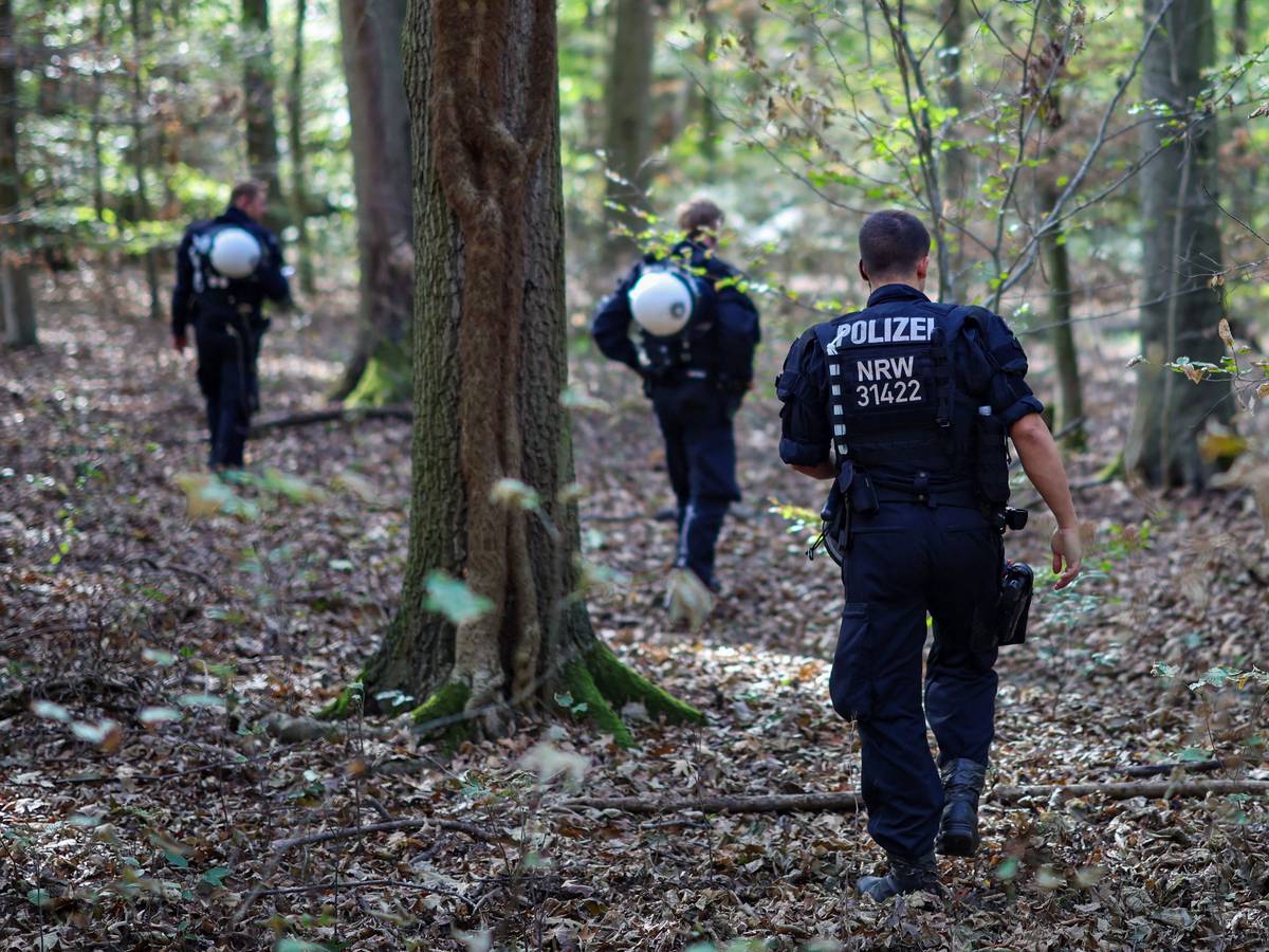 Polizeikräfte durchsuchen ein Waldstück.