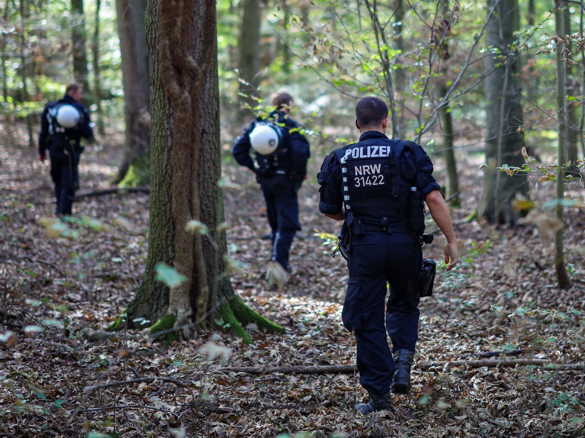 Polizeikräfte durchsuchen ein Waldstück.
