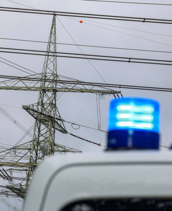 An einem Umspannwerk steht ein Polizeifahrzeug, von dem man aber nur das Blaulicht sieht.