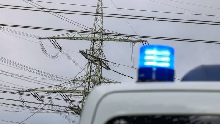 An einem Umspannwerk steht ein Polizeifahrzeug, von dem man aber nur das Blaulicht sieht.