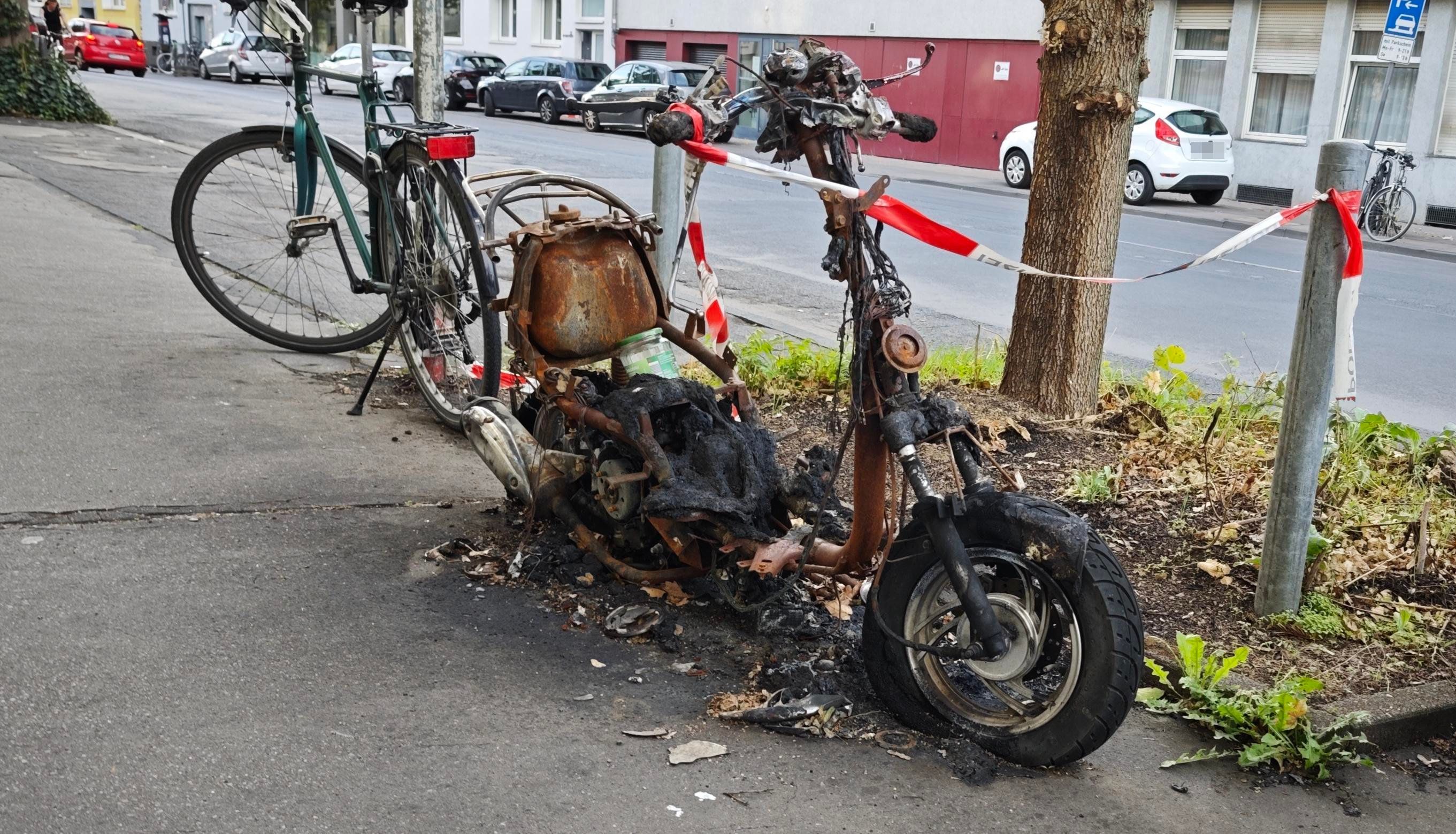 Ein ausgebranntes Motorrad steht in Lindenthal an der Straße.