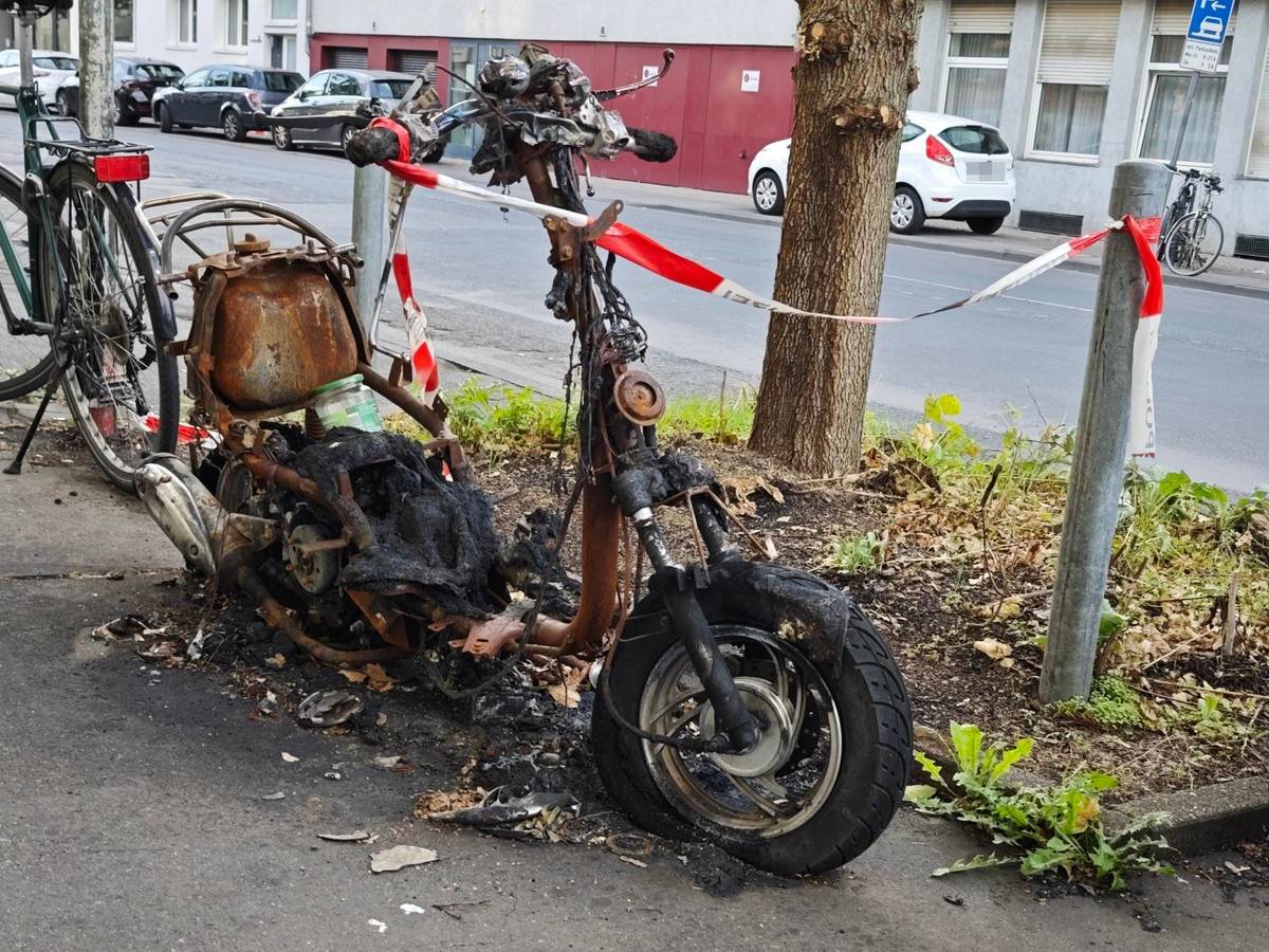 Ein ausgebranntes Motorrad steht in Lindenthal an der Straße.