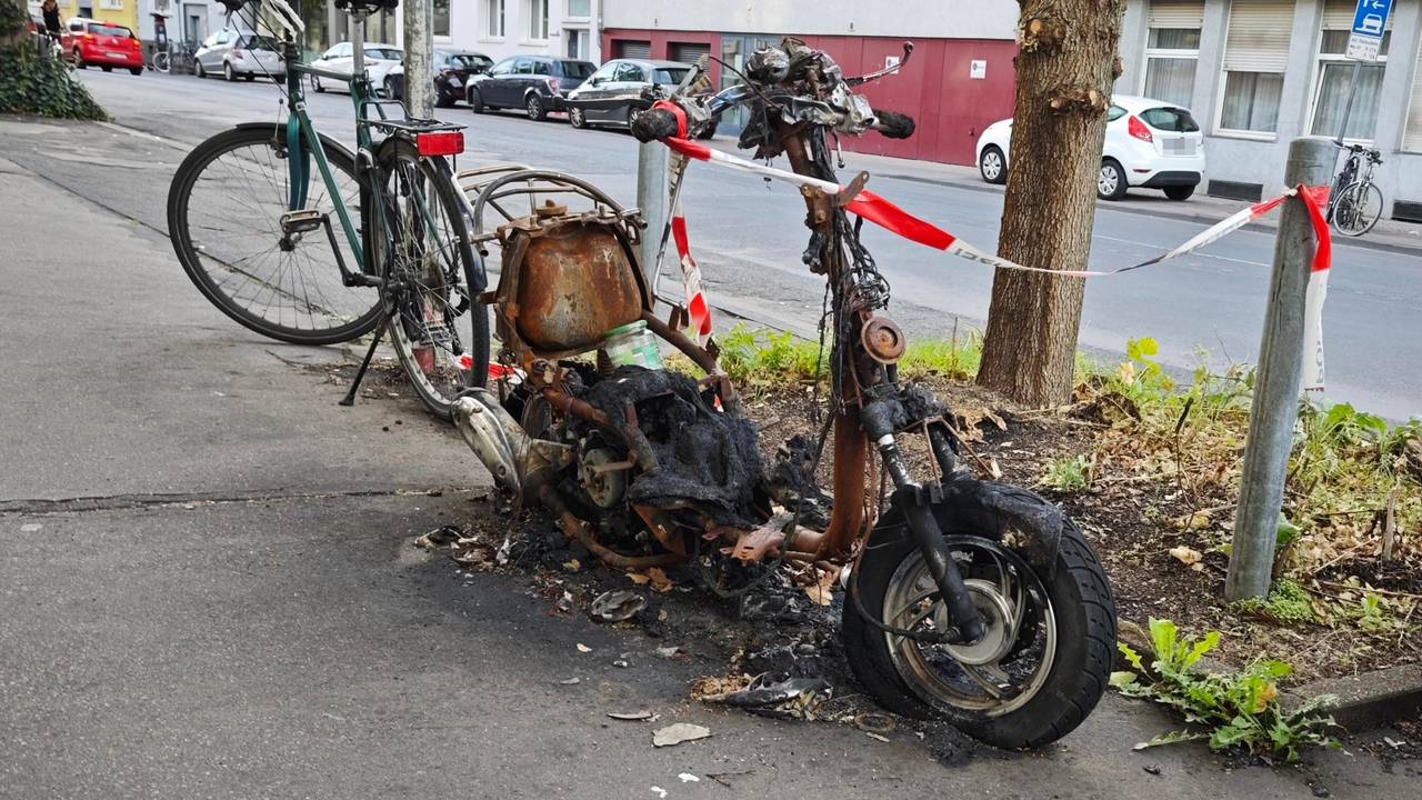 Ein ausgebranntes Zweirad-Wrack steht in Lindenthal an der Straße.