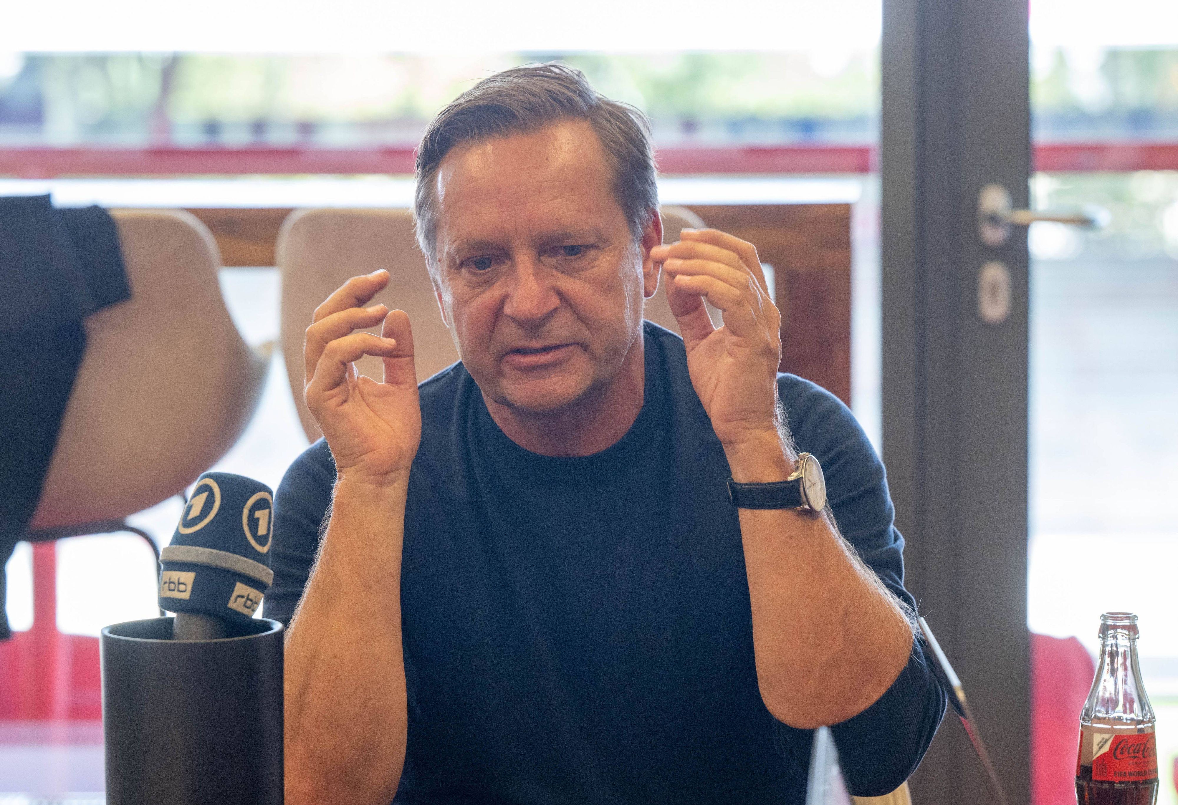 Horst Heldt gestikuliert bei einer Medienrunde.