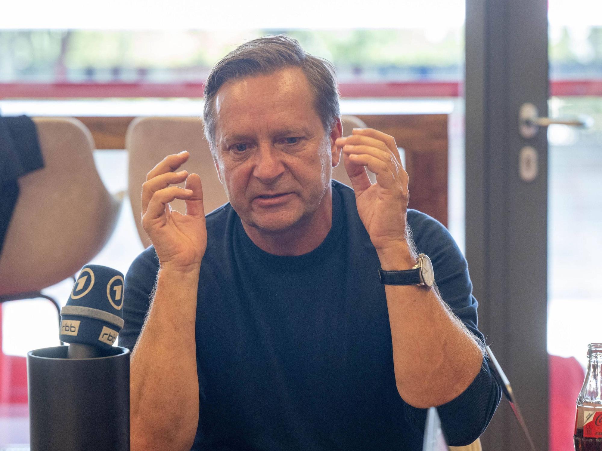 Horst Heldt gestikuliert bei einer Medienrunde.