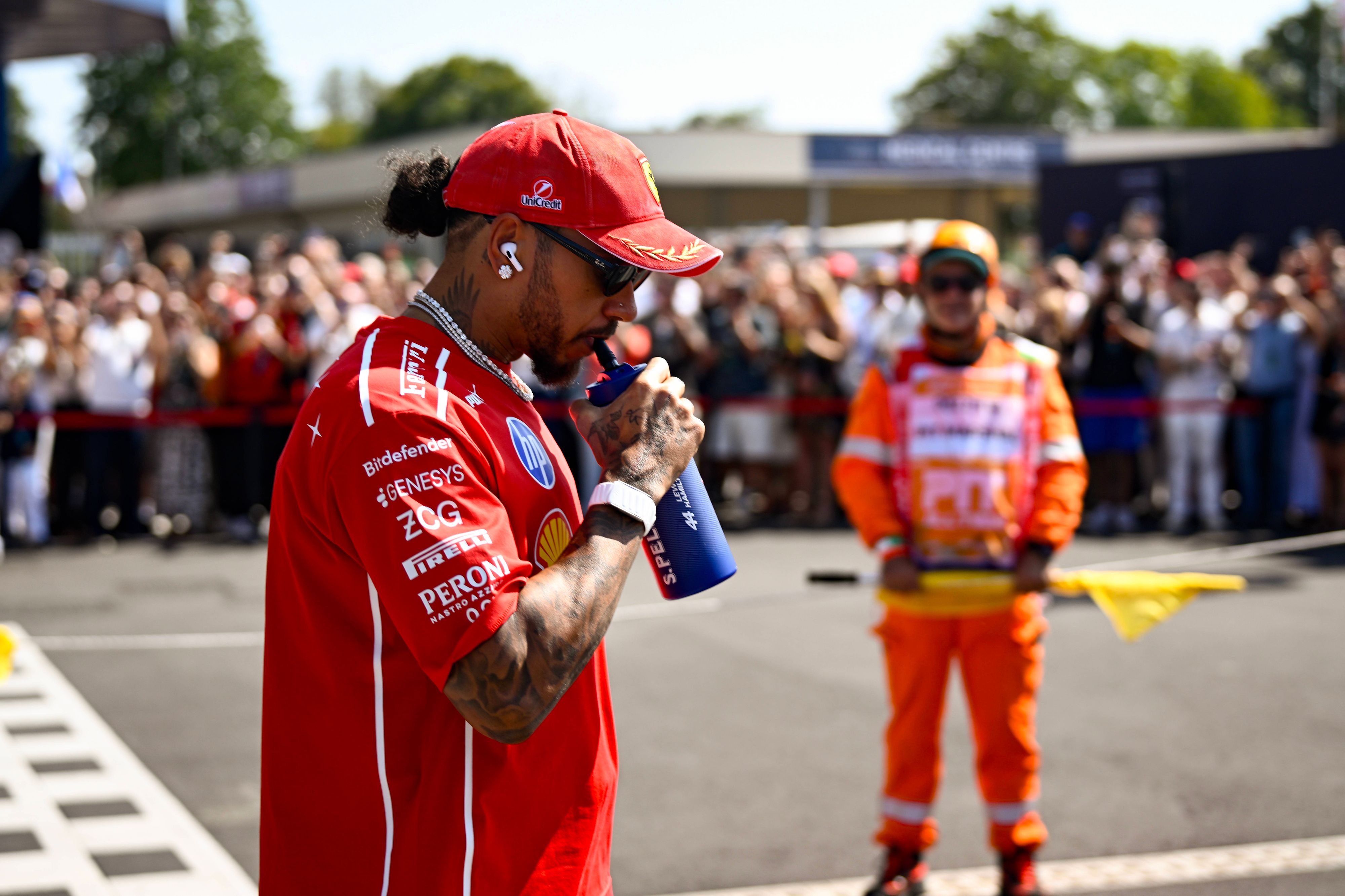 Lewis Hamilton trinkt an einer Flasche.